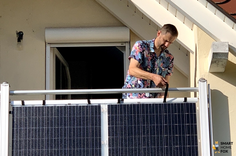Mann auf dem Balkon befestigt die Paneele mit Klettbändern